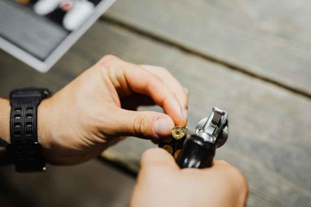 Hands of a person holding a gold bullet and a pistol