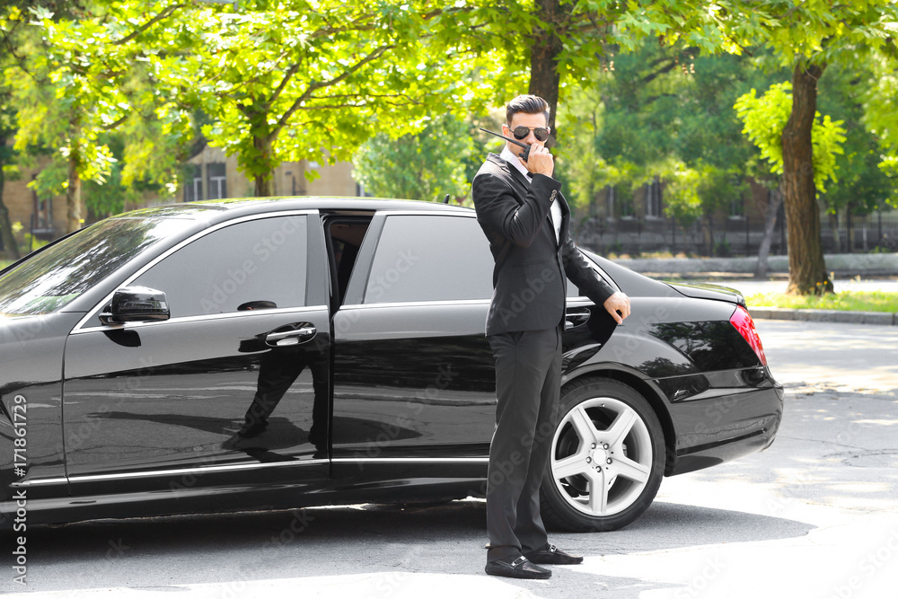 Handsome bodyguard near car outdoors